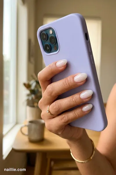 Close-up of oval nails with milky white polish and a glossy see-through jelly finish
