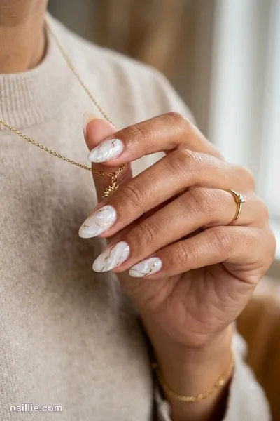Close-up of almond nails with milky white marble swirls with gold veins — look 2