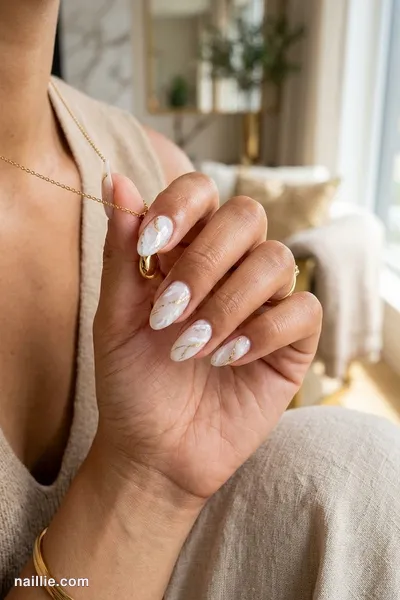 Close-up of almond nails with milky white marble swirls with gold veins — look 3