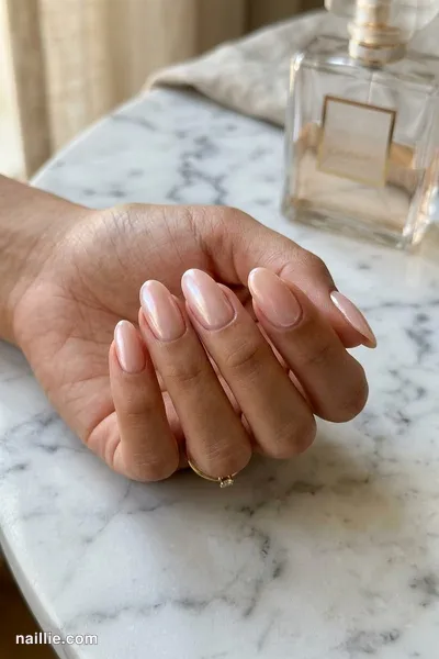 Close-up of oval nails with soft pink nude polish and a pearly glazed-donut shimmer