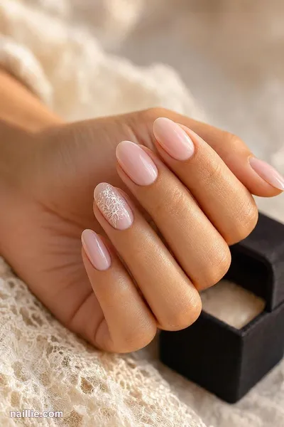 Close-up of soft pink nude nails with one sparkly glitter accent nail next to a ring box