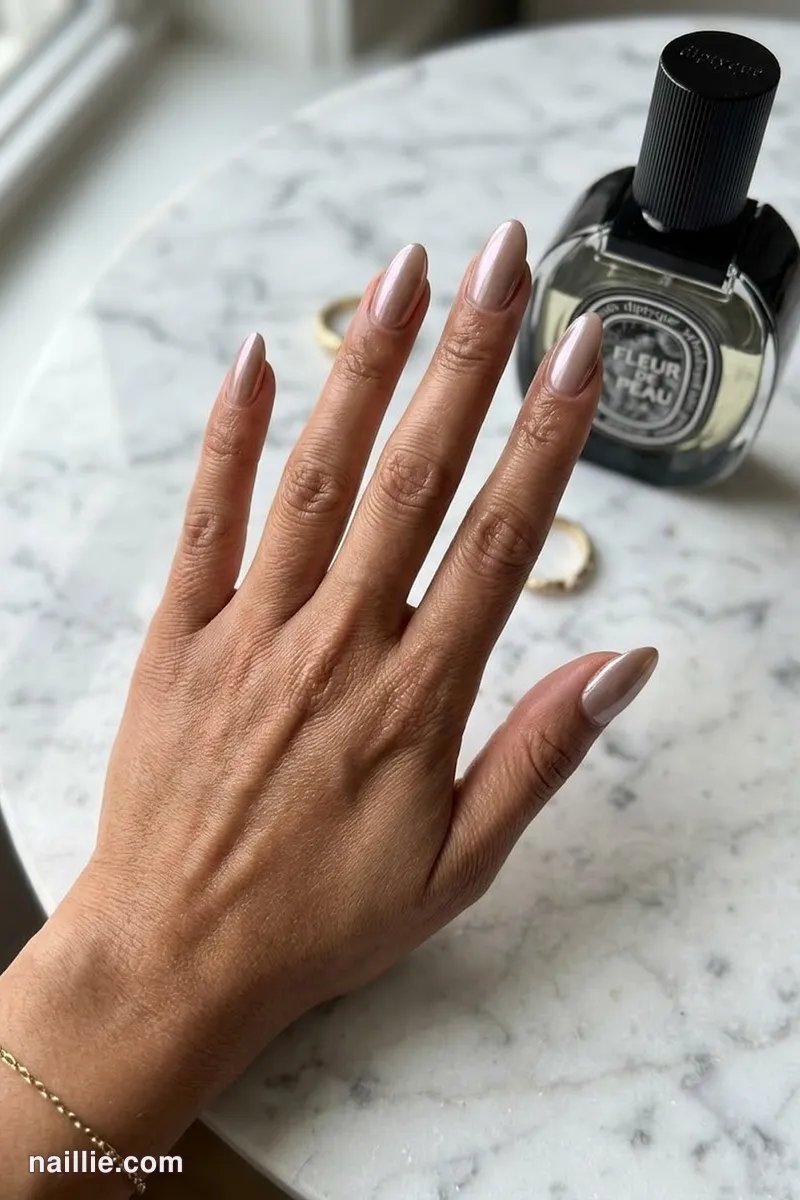 Close-up of almond nails with taupe polish and a pearly glazed-donut shimmer