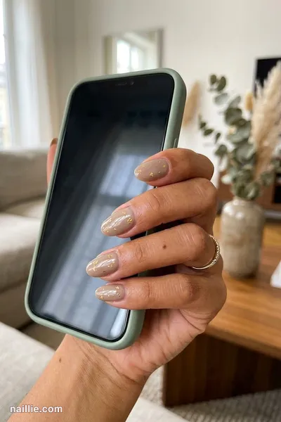 Close-up of oval nails with taupe polish and delicate gold foil flakes — look 3
