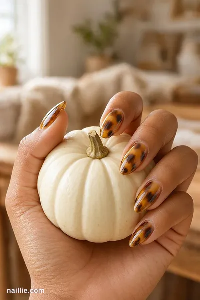 Close-up of almond nails with glossy amber-and-brown tortoiseshell print — look 3